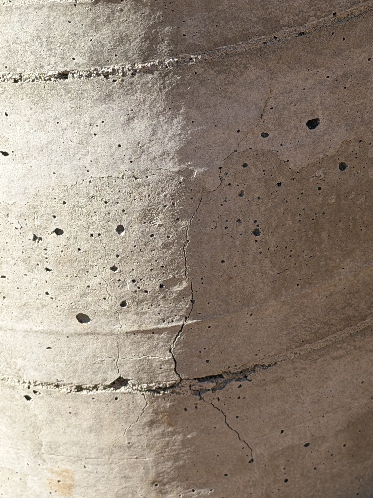 Close-up of a concrete pier surface showing a fine meandering crack that branches and changes direction.